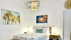 A bedroom with a bed, bedside tables, a bench, a hanging lamp, and wall art. - Tropical Private Beach Studio Apt #1 @ Jobos Beach (Jobos, Isabela, Puerto Rico)