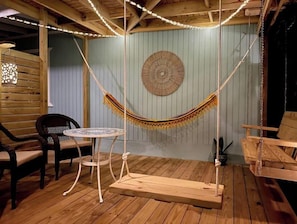 A cozy room with a hammock swing, a round woven wall decoration, and a small round table with chairs.
