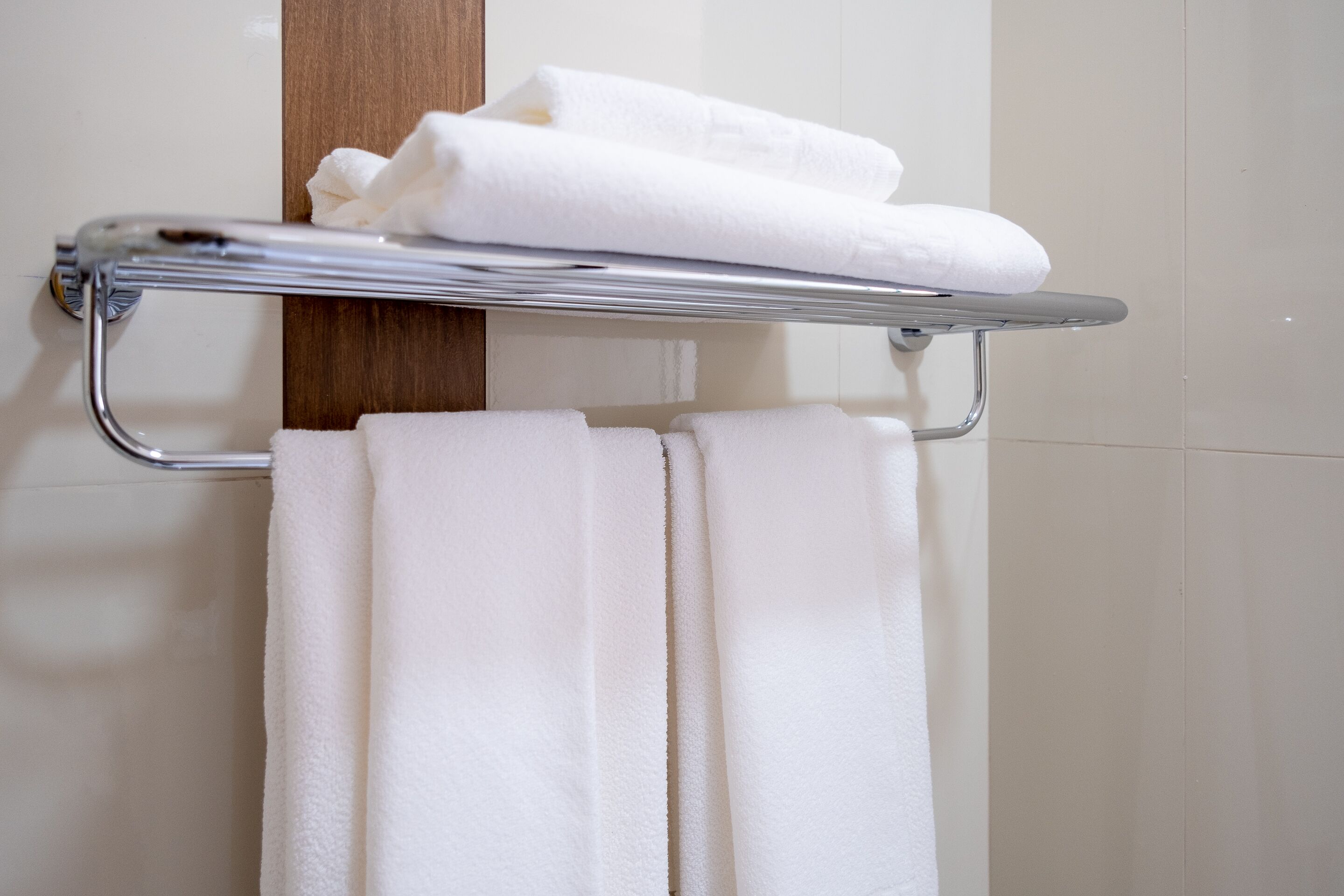 A bathroom with a towel rack holding folded towels.