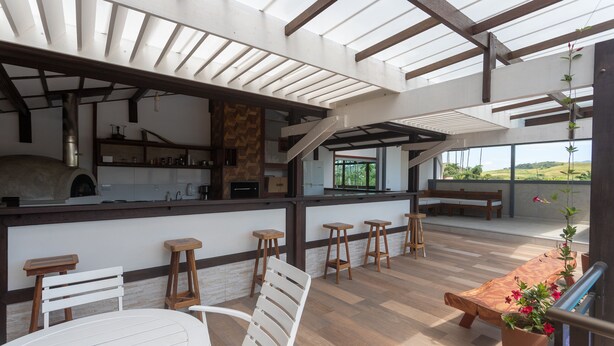 Une vaste terrasse dotée de meubles en bois, d’une cheminée en pierre et offrant une vue sur la campagne.