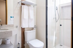 A modern bathroom with a glass shower enclosure, a toilet, and a sink with a towel rack. - Bliss Hotel Vale do Café (Vassouras)