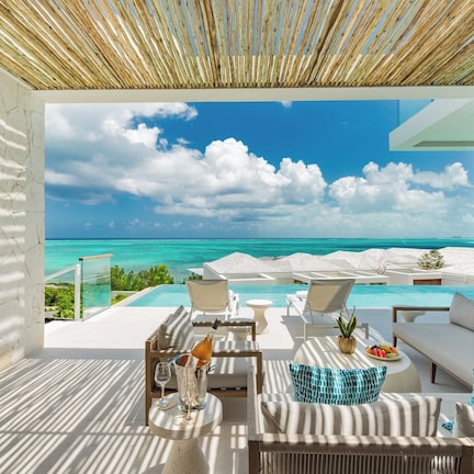 A luxurious outdoor lounge with a view of a turquoise ocean and clear blue sky.