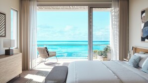 A bedroom with a large bed, a chair, a bedside table, and a view of the ocean. - Rock House (Providenciales)