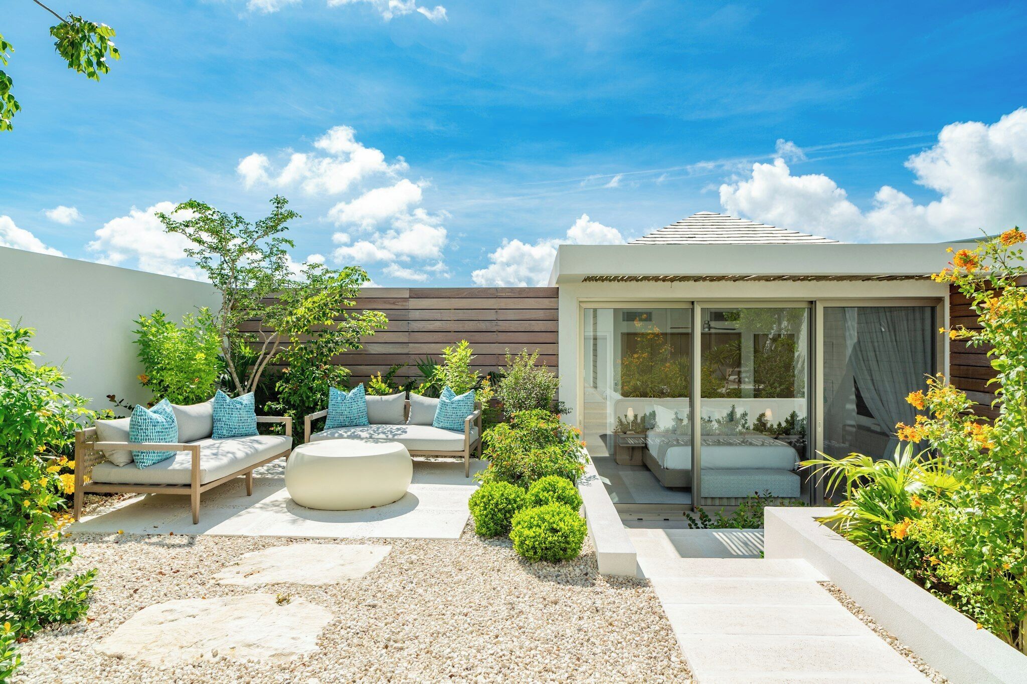 A modern outdoor patio with seating and a glass-enclosed room.
