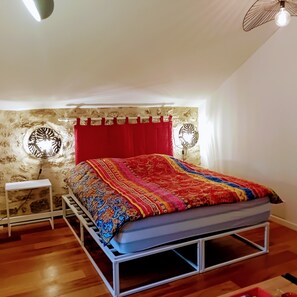 A bedroom with a bed, a small bedside table, a wall-mounted fan, and a red curtain. - LOFT Locronan 1624, renovated in 2021, in France's second most beautiful village   (Locronan)