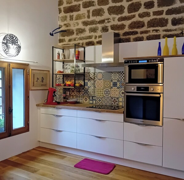 A kitchen with white cabinets, a double oven, and a patterned backsplash.