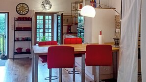 Ein Essbereich mit Steinwand, Holztisch, roten Stühlen und einer Hängelampe.