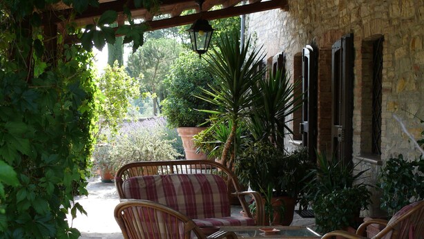 An outdoor patio with wicker furniture, a stone wall, and potted plants.