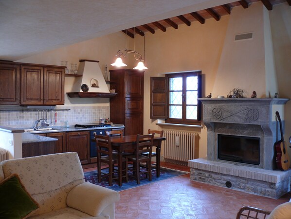 A kitchen with wooden cabinets, a stove, and a dining area with chairs and a table.