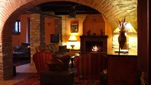A cozy living room with a fireplace, comfortable seating, and a stone archway.
