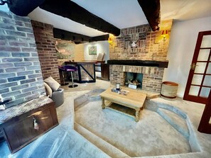 A cozy living room with a stone fireplace, a sofa, a coffee table, and a bar area.