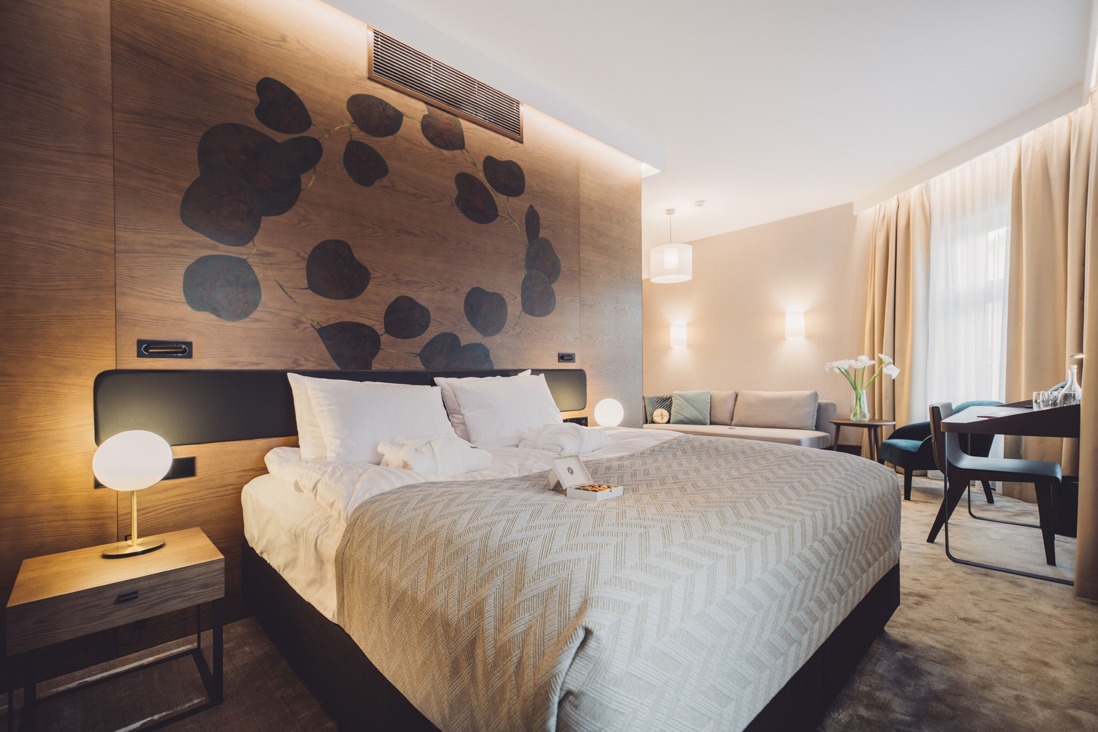 Una habitación de hotel moderna con una cama grande, un escritorio y un rincón de descanso.