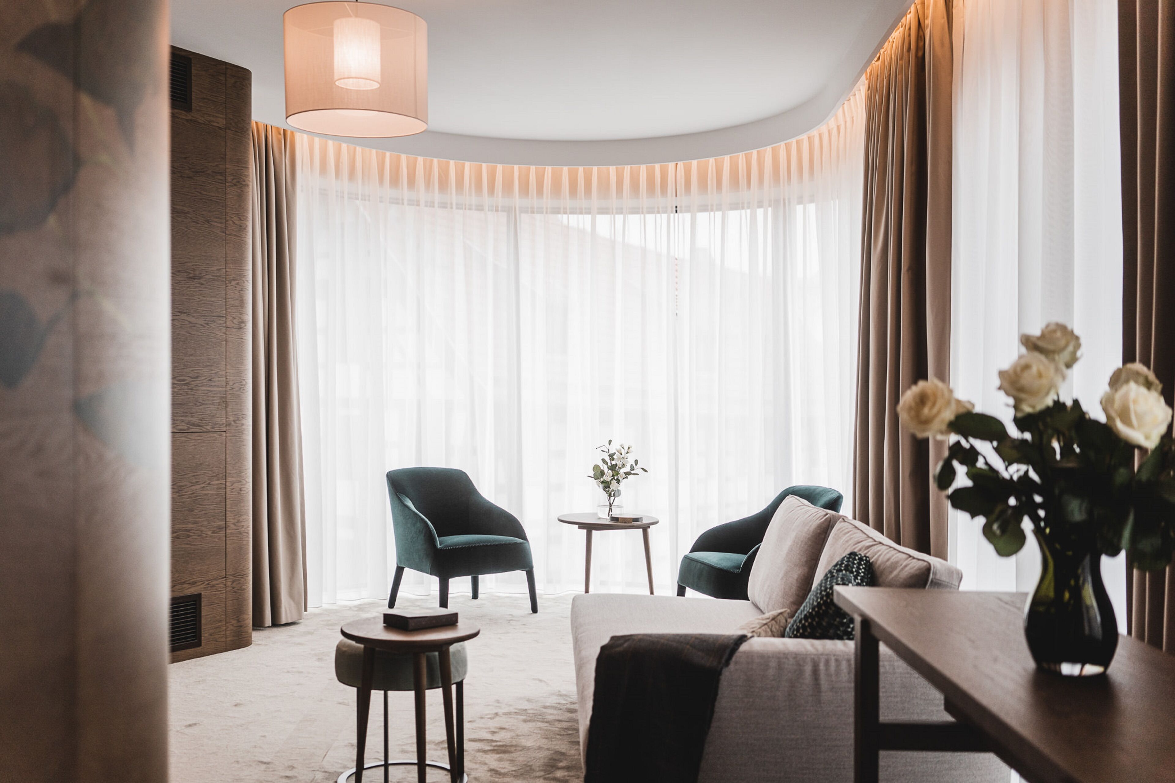 Una sala de estar moderna con un sofá, dos sillones, una mesita y un jarrón con flores.