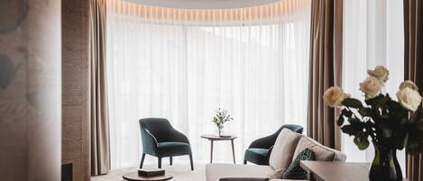 Una sala de estar moderna con un sofá, dos sillones, una mesita y un jarrón con flores.