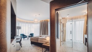 Une chambre d’hôtel moderne équipée d’un lit, d’un bureau, de chaises et d’une douche en verre.