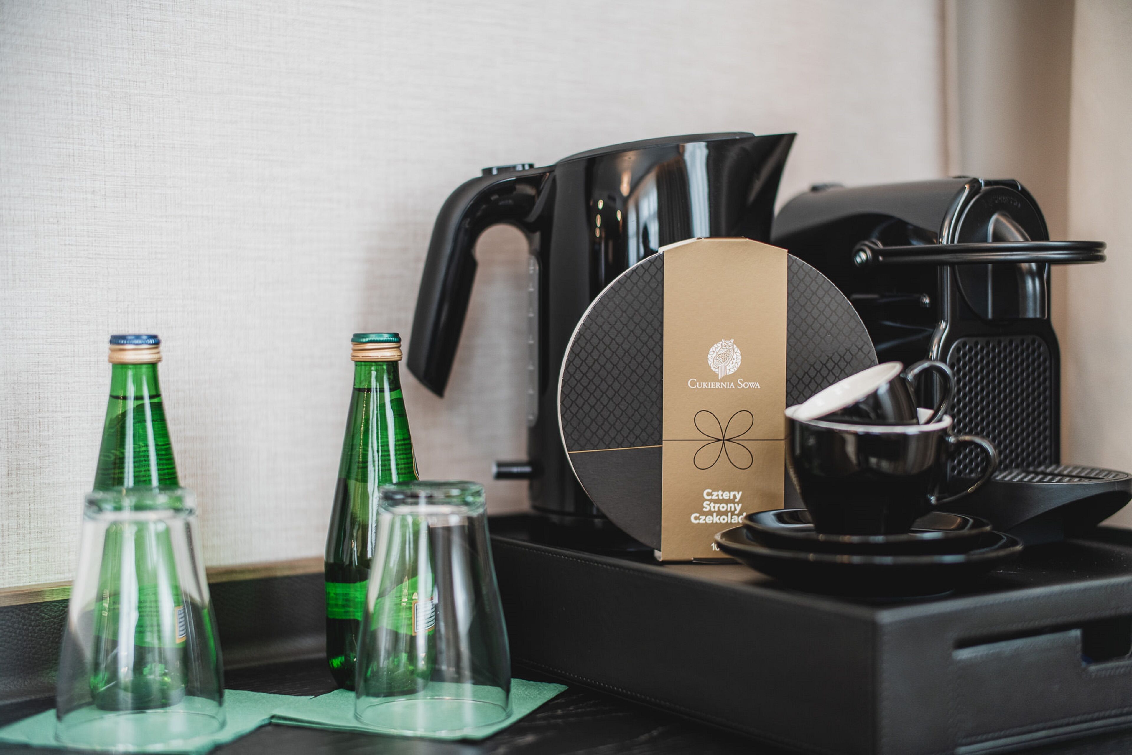 Una cafetera, dos botellas de vidrio y una caja sobre una mesa.