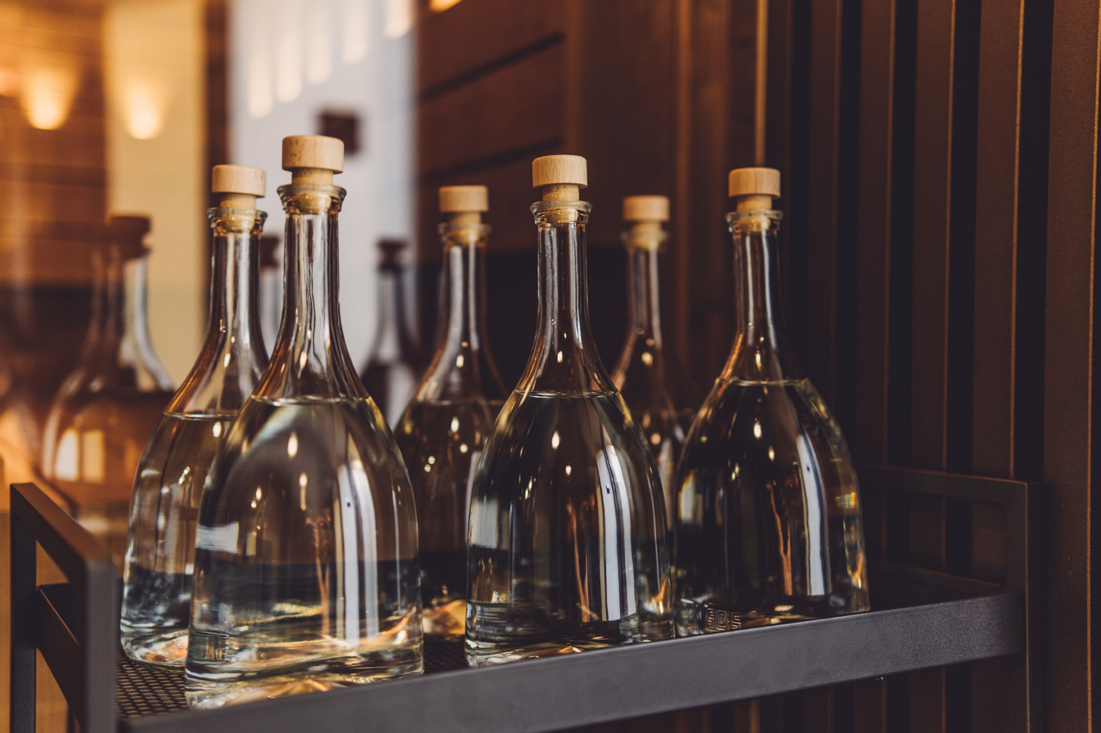 A row of empty wine bottles with corks on a shelf.