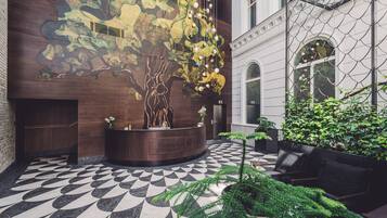 A reception area with a wooden reception desk, a mural of a tree, and a patterned floor.
