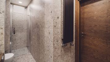 A bathroom with a shower, a toilet, and a wooden door.