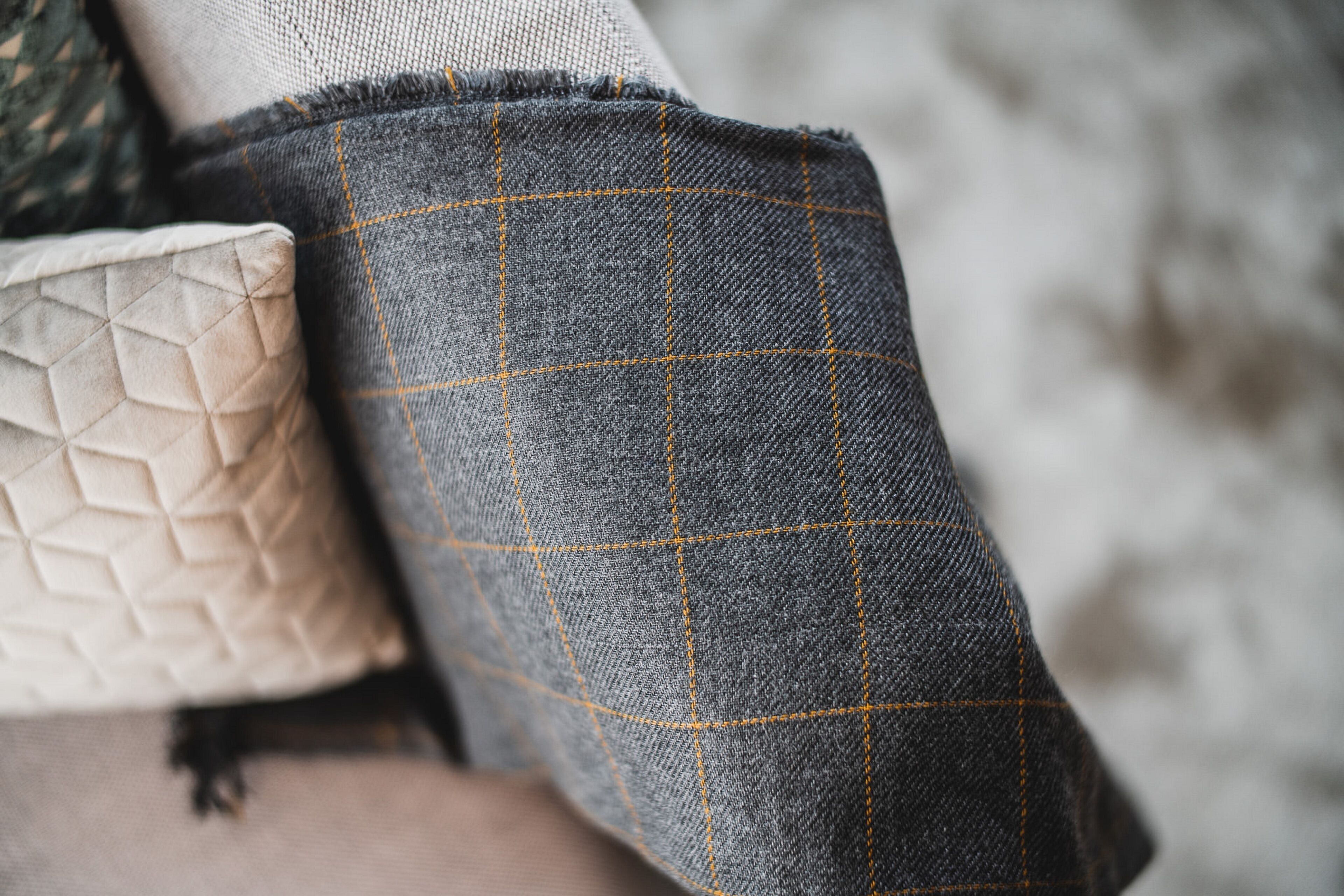 A close-up of a fabric with a grid pattern and a quilted pillow.