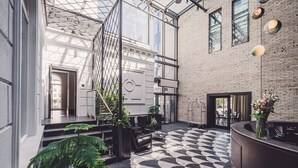 Un hall d’entrée moderne avec un sol à motifs géométriques, un comptoir d’accueil et des plantes d’intérieur.