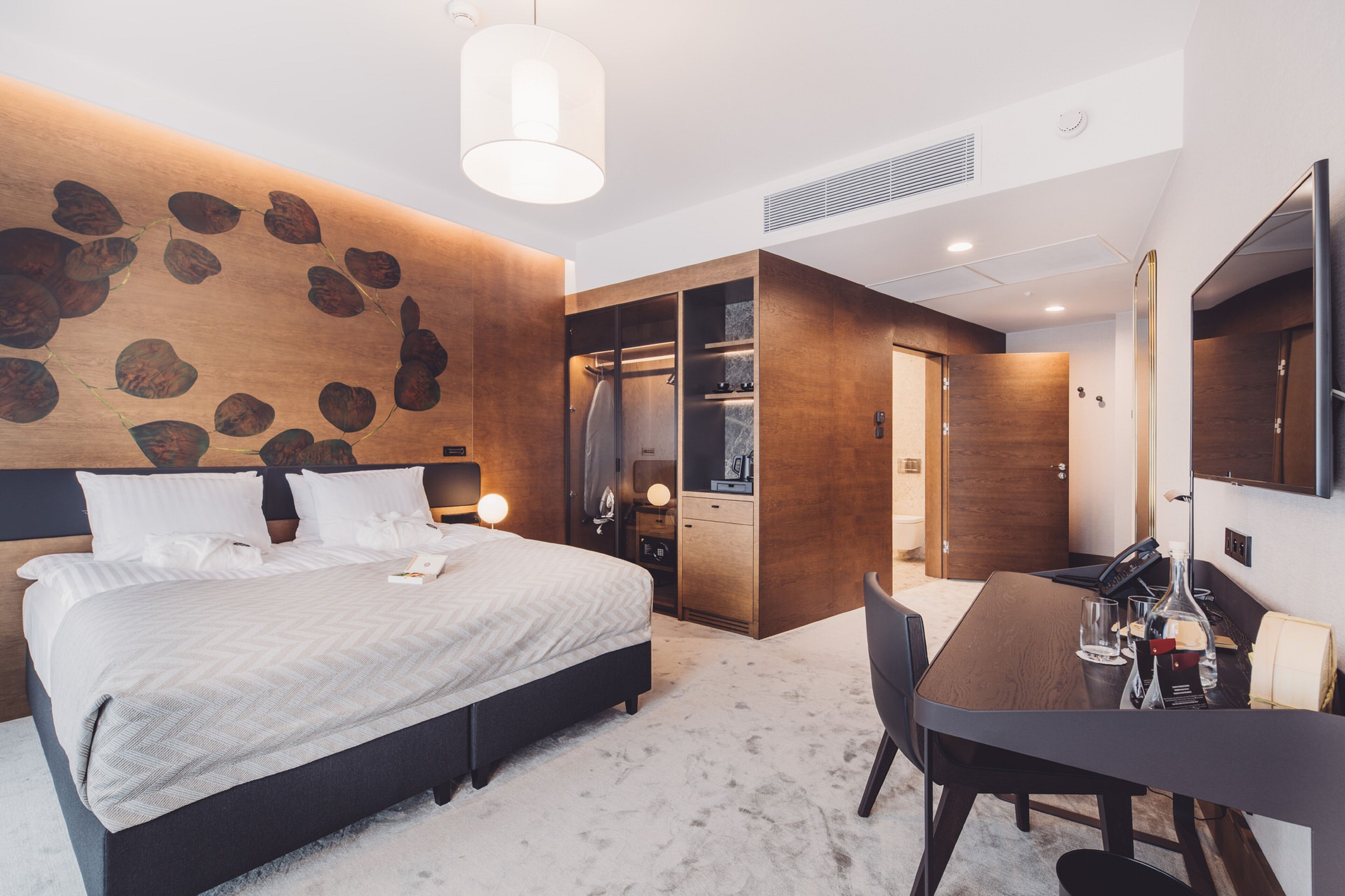 Habitació d'hotel moderna amb un llit gran, un escriptori i una zona de banyera.