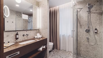 A modern bathroom with a marble sink, a glass shower enclosure, and a toilet.