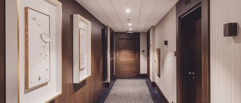 A hotel hallway with framed artwork on the walls, a checkered floor, and a door labeled "104".