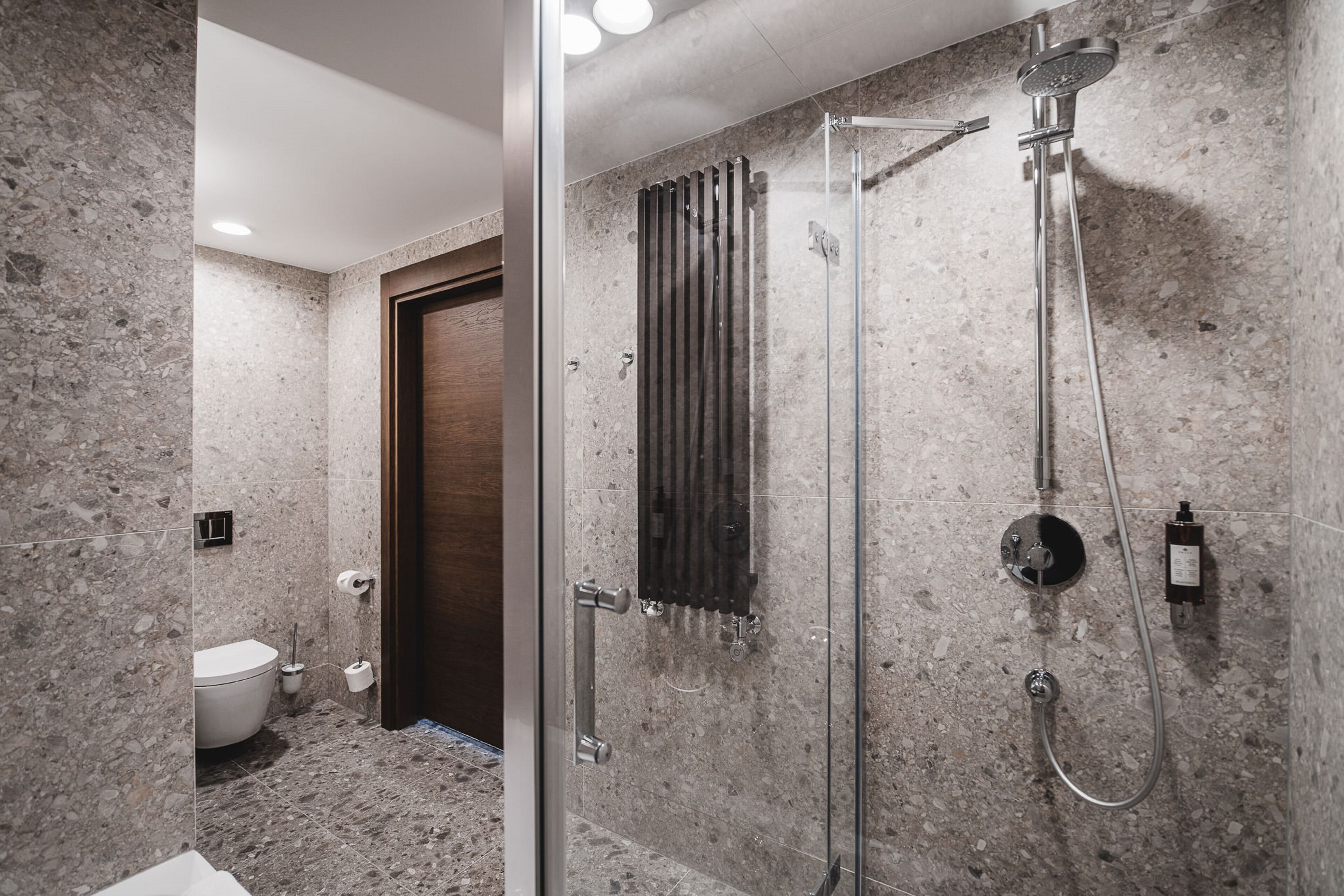 A modern bathroom with a glass-enclosed shower, a toilet, and a towel rack.