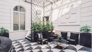 Un espace de détente intérieur moderne, avec un sol à motifs géométriques, des fauteuils en cuir noir, une table ronde et des plantes en pot.