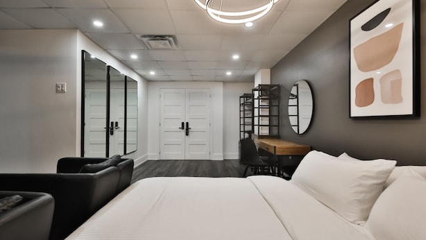 Une chambre d’hôtel moderne, dotée d’un grand lit, d’un bureau avec une chaise, d’une armoire et d’un miroir mural.