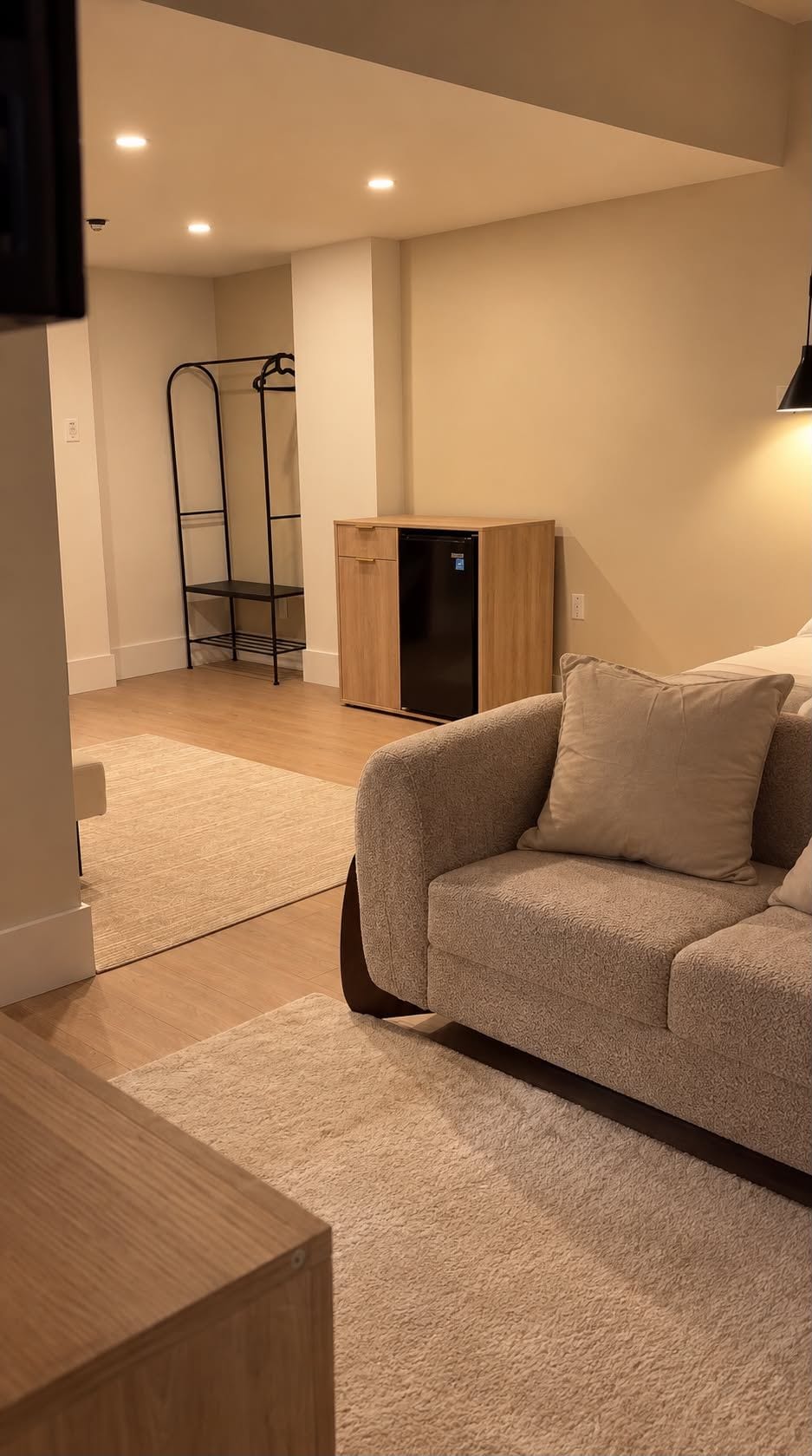 Una sala de estar con un sofá, un aparador de madera y una estantería metálica.