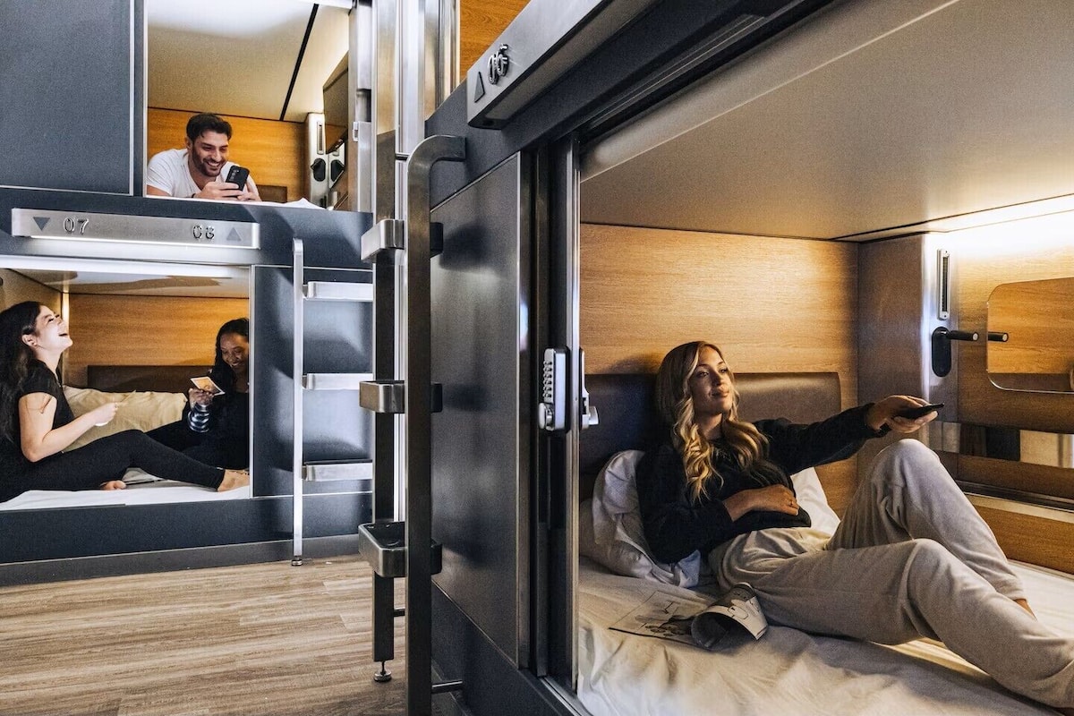 Un compartiment de train moderne équipé d’un lit superposé, d’une petite kitchenette et d’une fenêtre.