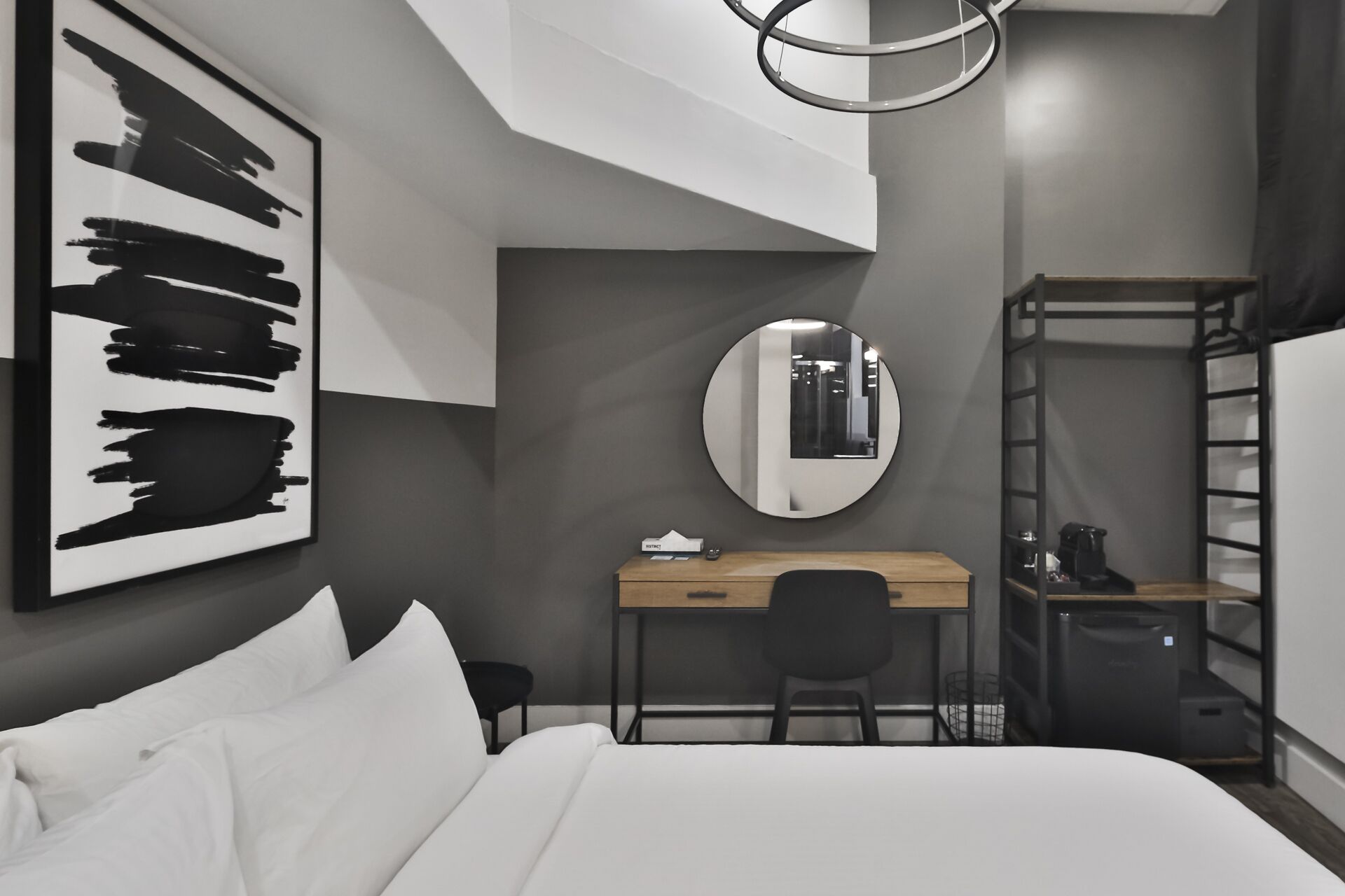 Un dormitorio moderno con cama, escritorio, silla, espejo redondo y literas.