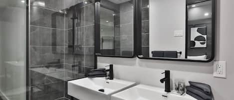 Une salle de bain moderne avec deux lavabos, une douche en verre et trois miroirs.
