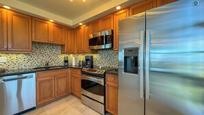 A modern kitchen with wooden cabinets, a stainless steel refrigerator, a microwave, a coffee maker, and a dishwasher. - South Seas Tower 4- 812: Beautifully Updated; Large Balcony (Marco Island)