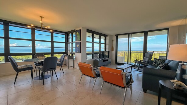 A spacious living area with large windows offering ocean views, a dining table with chairs, and a seating area with a sofa and armchairs. - South Seas Tower 4- 812: Beautifully Updated; Large Balcony (Marco Island)