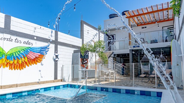 A swimming pool with water jets, a colorful mural, and outdoor seating.