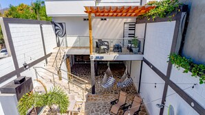 A modern outdoor patio with a stone floor, seating area, and a pergola.