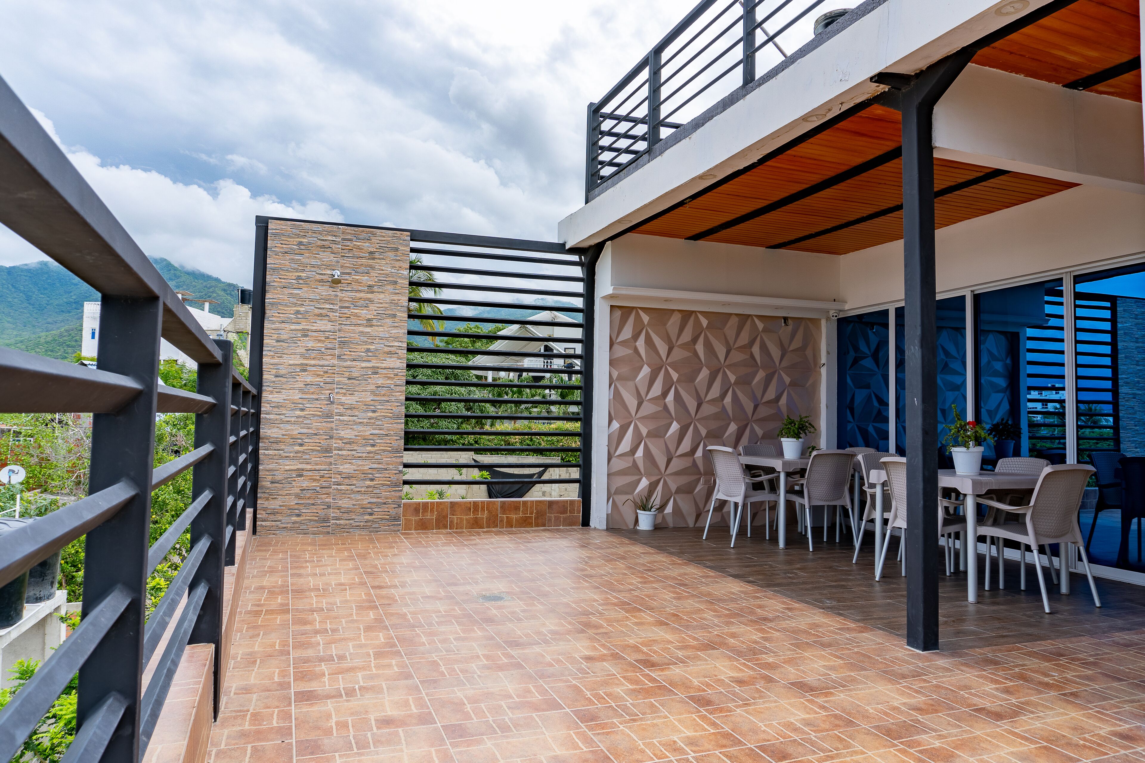 Een terras buiten met een eethoek en uitzicht op de bergen, met een modern architectonisch ontwerp.