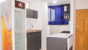 Cocina compacta con refrigerador, lavamanos y una pequeña encimera.