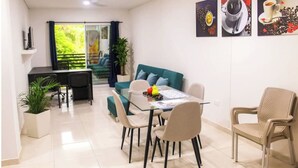 Un comedor moderno con una mesa de vidrio, sillas y un sofá color turquesa.