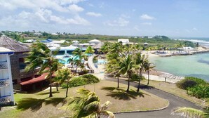 A resort with a pool, palm trees, and a beach view. - Studio NIKITA-MANGANAO , sea view, swimming pool (Saint-François)
