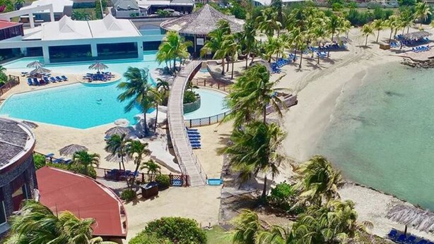 A resort with a swimming pool, beach, and palm trees. - Studio NIKITA-MANGANAO , sea view, swimming pool (Saint-François)