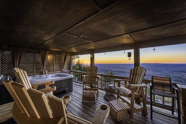 Une terrasse en bois avec un jacuzzi, des chaises en bois et une vue sur le paysage.