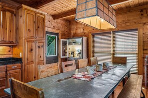 A wooden interior with a dining table, chairs, and a kitchen area with cabinets and a refrigerator.