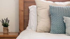A neatly made bed with white bedding, a wooden headboard, and two pillows. A small plant is on a wooden nightstand beside the bed. - ◆ Sensational Apartment! 2 Bed 1 Bath - Sleeps 4 ◆ (Colorado Springs)