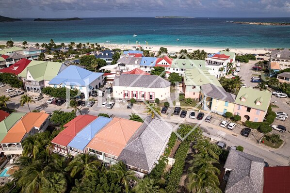 An aerial view of a coastal town with colorful buildings, a beach, and a clear view of the ocean. - Very nice 2 bed-rooms apartment at Orient Beach (Collectivité de Saint-Martin)