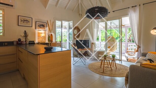 A spacious living area with a kitchen island, a dining table with chairs, and a large window providing a view of the outdoors.
