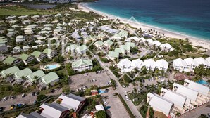 An aerial view of a coastal resort with multiple buildings, a beach, and a clear view of the ocean.